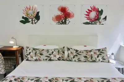 a bedroom with a bed with three flowers on the wall at Pecan Tree Forest Studio A in Stellenbosch
