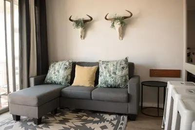 a living room with a couch and antlers on the wall at Easy Going Hermanus With An Ocean View in Hermanus