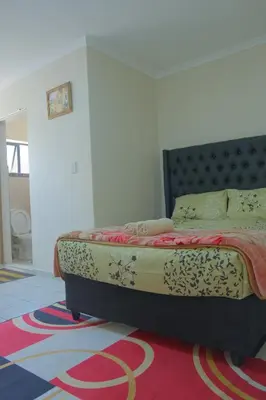 a bedroom with a bed on a colorful carpet at Supa Guesthouse in Parow