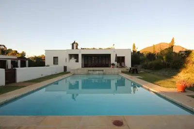 a swimming pool in front of a house at Mitre's Edge Pool House in Klapmuts