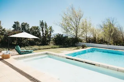 a swimming pool with a chair and an umbrella at Mitre's Edge Pool House in Klapmuts