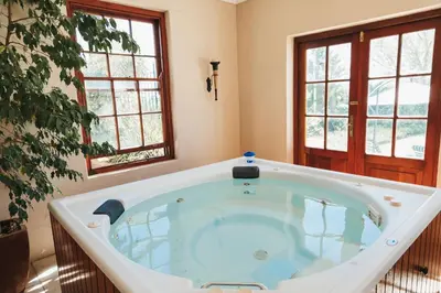 a large bath tub in a room with two windows at Mitre's Edge Pool House in Klapmuts