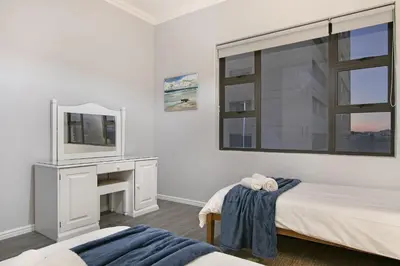 a white bedroom with a bed and a mirror at Jacquelena Hof 9 in Strand