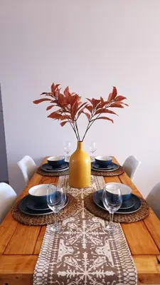 a wooden table with a vase with wine glasses on it at Villa Nordica - 2 bedroom self-catering apartment in Cape Town