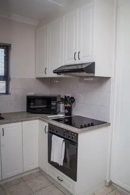 a kitchen with white cabinets and a stove top oven at Villa Nordica - 2 bedroom self-catering apartment in Cape Town