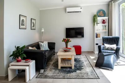 a living room with a couch and a table at Tortelduif Cottage in Stellenbosch