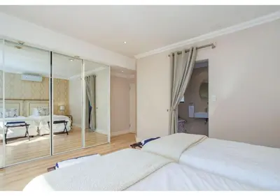 a bedroom with a large white bed and a mirror at Florin’s Crest 3 Bedroom Villa, Franschhoek in Franschhoek
