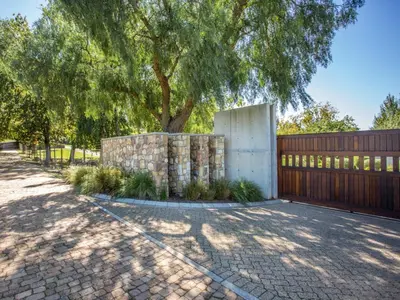 a fence with a tree next to a sidewalk at Wechmarshof in Stellenbosch