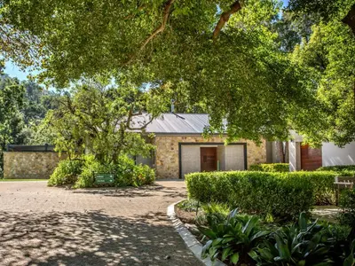 a brick building with a garage and a tree at Wechmarshof in Stellenbosch