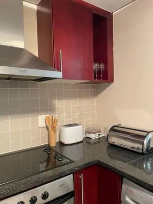 a kitchen with red cabinets and a counter top at Beautiful Ocean View Apartment in Cape Town