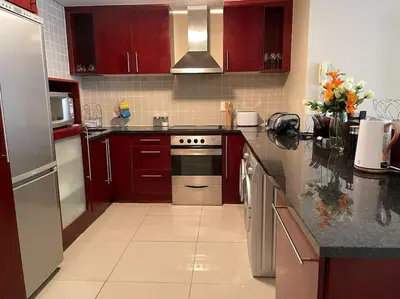 a kitchen with red cabinets and a stove top oven at Beautiful Ocean View Apartment in Cape Town