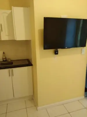 a flat screen tv on the wall of a kitchen at Jacmo Guest house in Cape Town