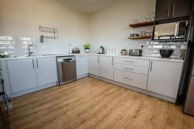 a kitchen with white cabinets and a wooden floor at Escape to Pringle in Pringle Bay
