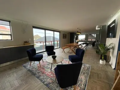 a living room with chairs and a table and windows at Escape to Pringle in Pringle Bay