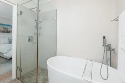 a white bathroom with a shower and a tub at Mountain View by Top Destinations Rentals in Hermanus
