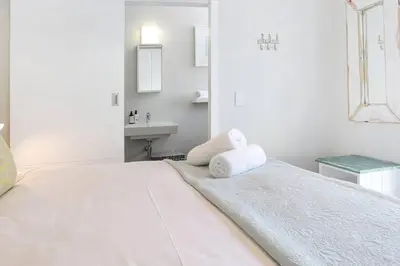 a white bedroom with a bed and a sink at Kingklip by Top Destinations Rentals in Hermanus