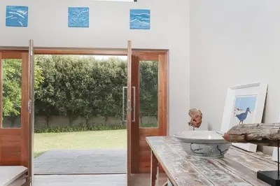 a room with a glass door and a sink on a table at Kingklip by Top Destinations Rentals in Hermanus