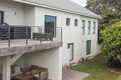 a white building with a deck with a bench on it at Kingklip by Top Destinations Rentals in Hermanus