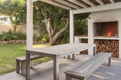 a picnic table on a patio with a fireplace at Kingklip by Top Destinations Rentals in Hermanus