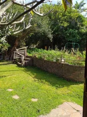 a garden with a brick wall and a fence at Garden cottage in Cape Town