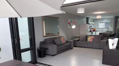 a living room with two couches and a kitchen at Cap du Mont in Bloubergstrand