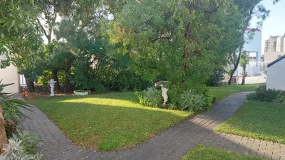 a garden with a brick path and trees and grass at Cap du Mont in Bloubergstrand