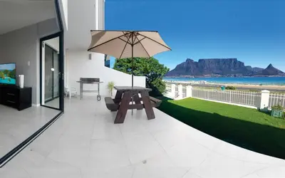 a patio with a table and an umbrella at Cap du Mont in Bloubergstrand