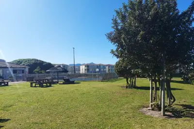 a park with benches and a tree in the grass at First Group Hermanus Beach Club in Hermanus
