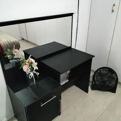a black dresser with a mirror and flowers on it at Naledi homestay in Cape Town