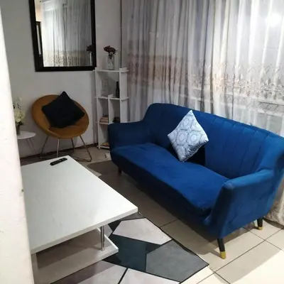 a blue couch in a living room with a table at Naledi homestay in Cape Town