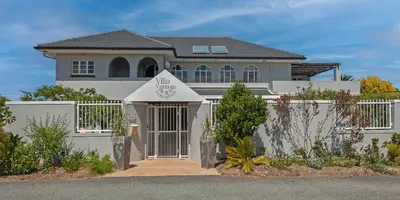 a white house with a gate and a fence at Villa Venusta Luxury Guesthouse - Solar Power in Hermanus
