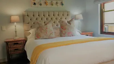 a bedroom with a large white bed with two lamps at Aan De Vliet Guest House in Stellenbosch