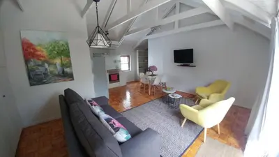 a living room with a couch and chairs and a tv at Aan De Vliet Guest House in Stellenbosch