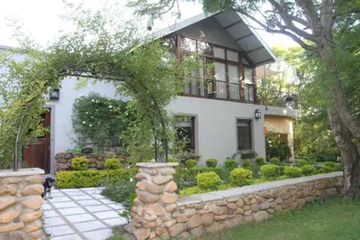 a house with a stone wall and a balcony at Aan De Vliet Guest House in Stellenbosch