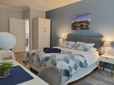 a bedroom with a bed with a blue and white comforter at Leafy Retreat Kenridge in Durbanville