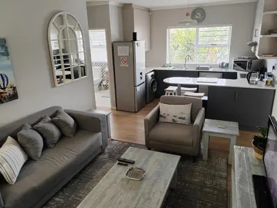 a living room with a couch and a kitchen at Leafy Retreat Kenridge in Durbanville