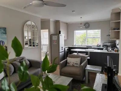 a living room with a couch and a kitchen at Leafy Retreat Kenridge in Durbanville