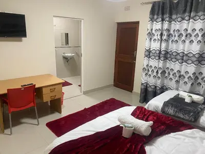 a bedroom with a bed and a desk and a desk at SABATH LODGE TWO in Cape Town
