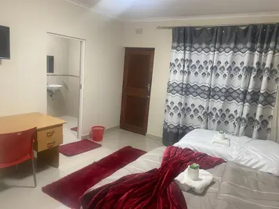 a bedroom with a bed and a desk and a sink at SABATH LODGE TWO in Cape Town
