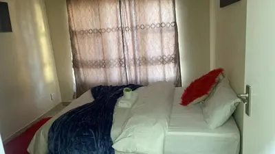 a small bed with white sheets and pillows and a window at SABATH LODGE TWO in Cape Town