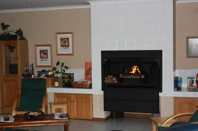 a living room with a fire in a fireplace at Old Oak Guest House in Bellville