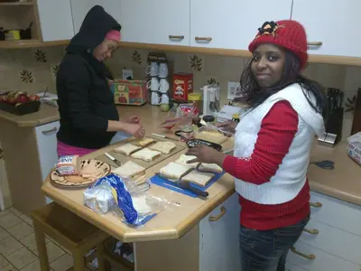 two women standing in a kitchen preparing food at Old Oak Guest House in Bellville