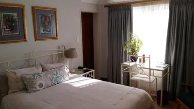 a bedroom with a bed and a window with a plant at Old Oak Guest House in Bellville