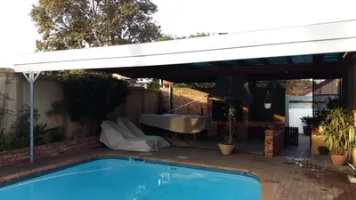 a white awning over a swimming pool with a tub at Old Oak Guest House in Bellville