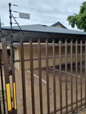 a fence in front of a building with a roof at Old Oak Guest House in Bellville
