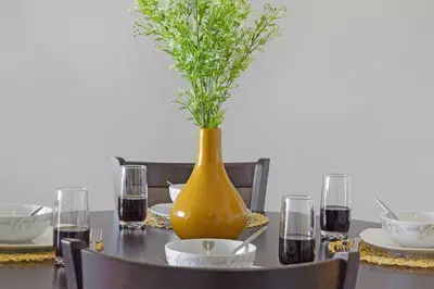 a table with a yellow vase with a plant in it at Lagoon Beach 302A in Cape Town