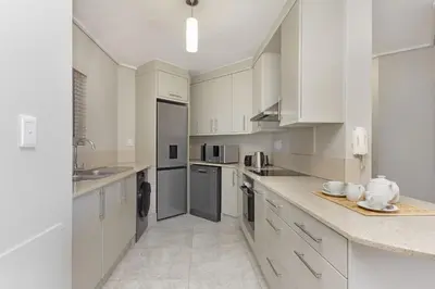 a white kitchen with white cabinets and appliances at Lagoon Beach 302A in Cape Town