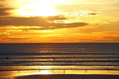 a sunset over the ocean with people surfing at Lagoon Beach 302A in Cape Town