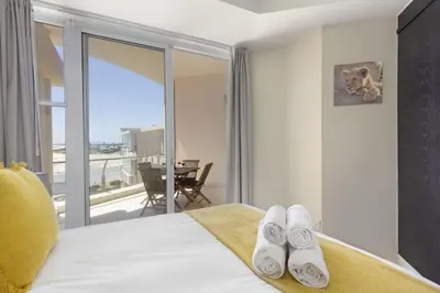 a hotel room with a bed with a balcony at Lagoon Beach 302A in Cape Town