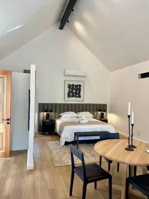 a bedroom with a bed and a table and chairs at Mountain Cottages at Haskell Vineyard in Stellenbosch